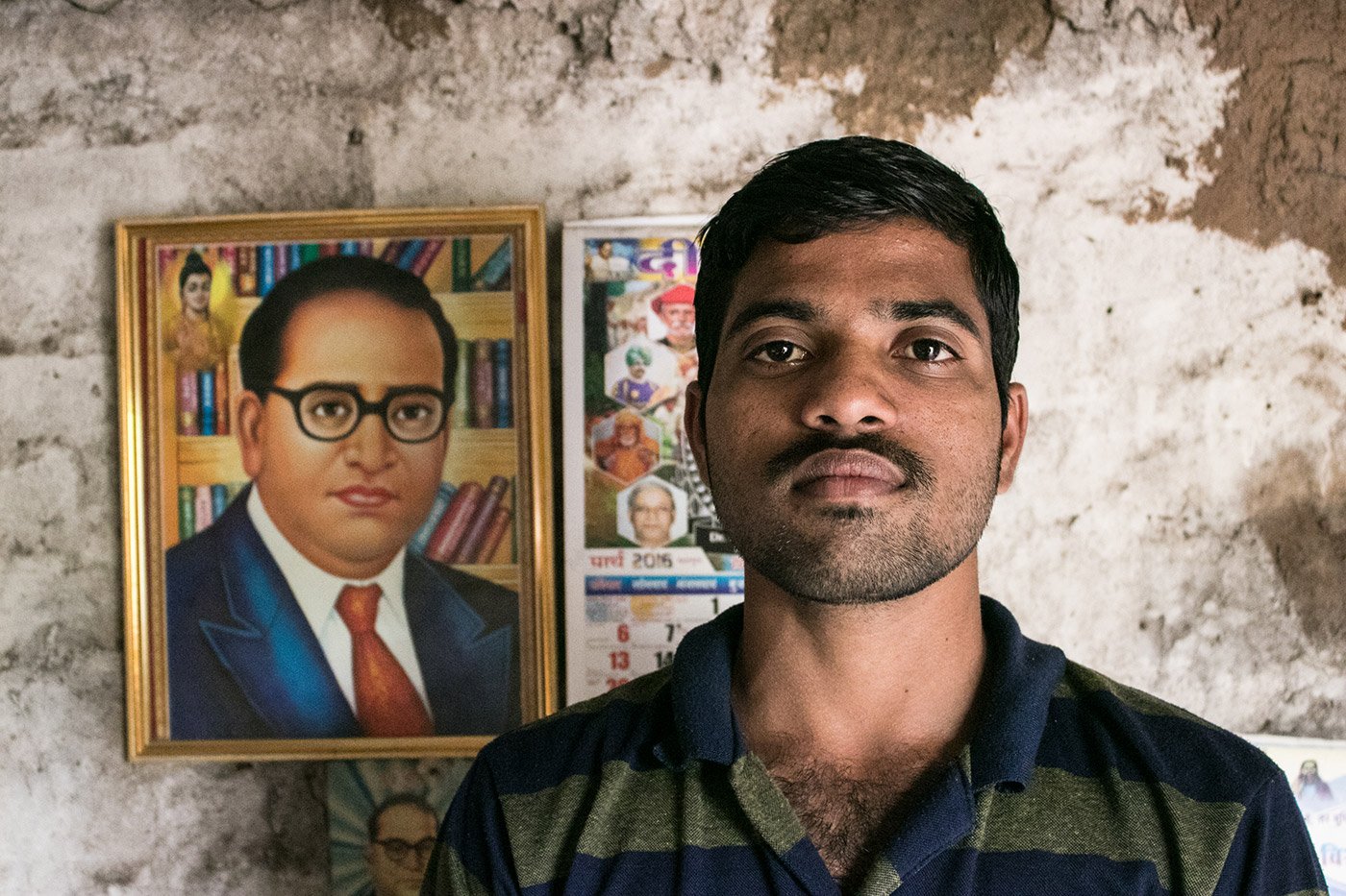 A young man standing in front of a framed illustration of Dr B. R. Ambedkar