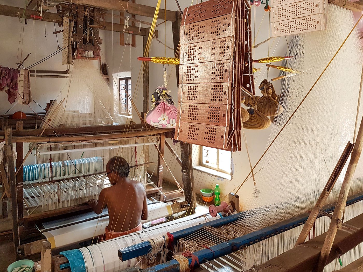 Mani works on a loom inside his home.