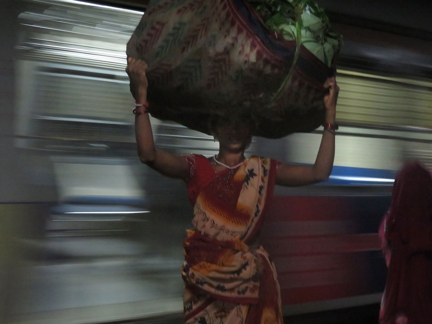 Tulshi, carrying a 35 kg load of palash leaves wrapped in an old sari, at the train station