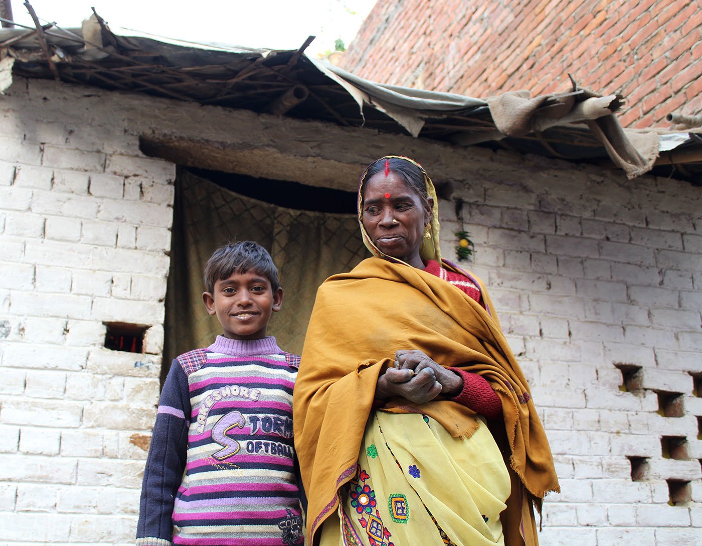 A woman and her son stand outside their house