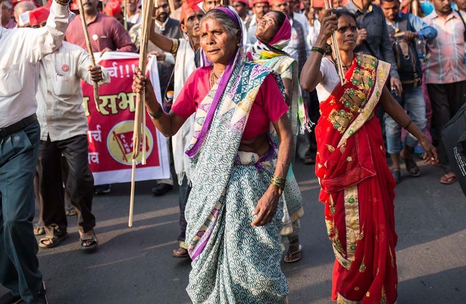 A woman marching alongside other people, holding a flag