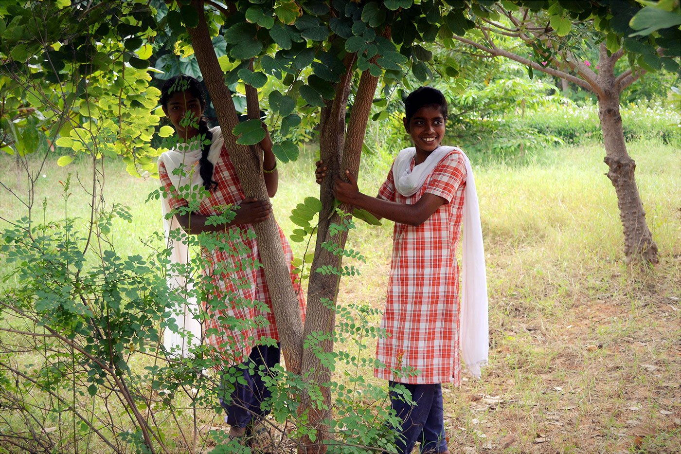 Two girls standing under a tree