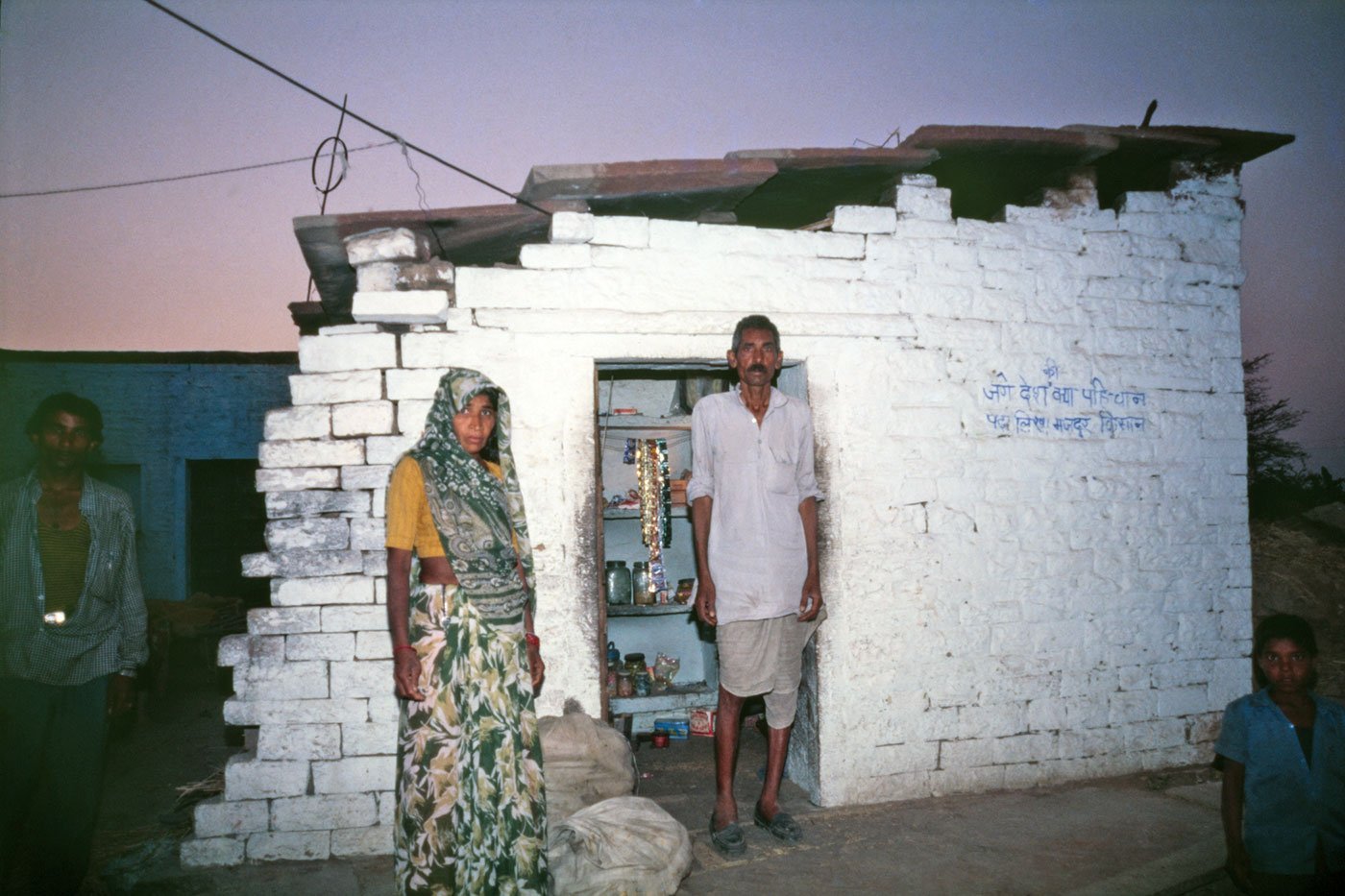 Mangi Lai Jatav and his wife in Naksoda village in Dholupur district. A man and a woman standing outside a hut