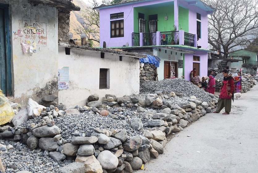 Woman on road outside house. Road lined with stacked stones