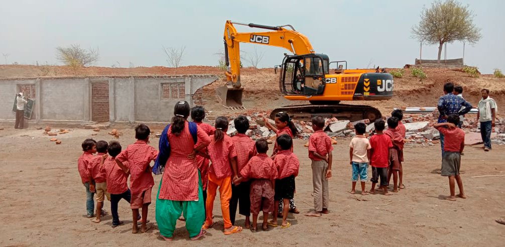 Schoolchildren looking at the bulldozer demolish their school