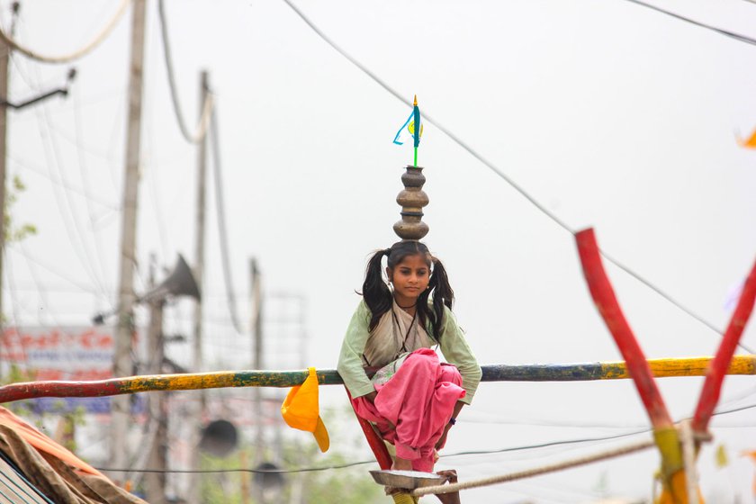 Rani Nat gets ready to walk on the wobbling cable with a plate beneath her feet. She moves with a long wooden staff, balancing brass pots on her head