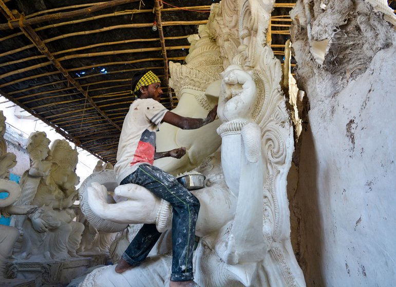 Babban sitting on the hand of a ganesh idol and painting it