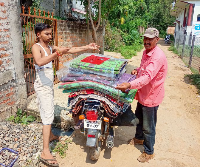 Bachu (with his son Puspraj on the left) visits 9-10 villages across 30 to 50 kilometres on his motorcycle to sell sarees, chatais and other items