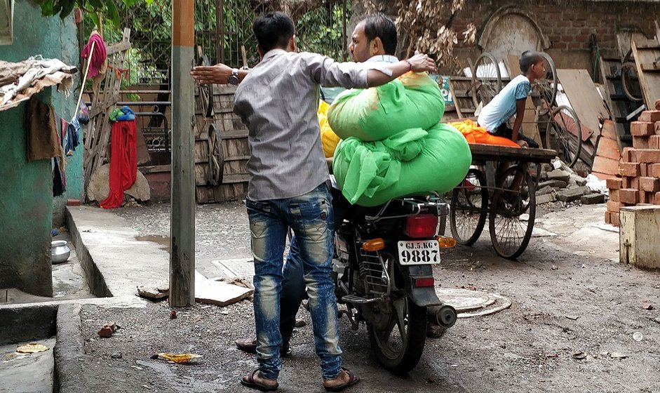 Men getting bundles of saris to the ladies who work on them