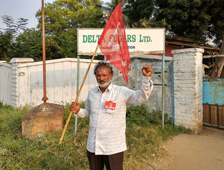 Man holding flag outside the gate of the Delta Sugars factory. he is protesting the closure of the company.