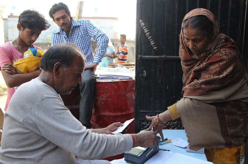 A man taking fingerprints on a machine for Aadhaar verification