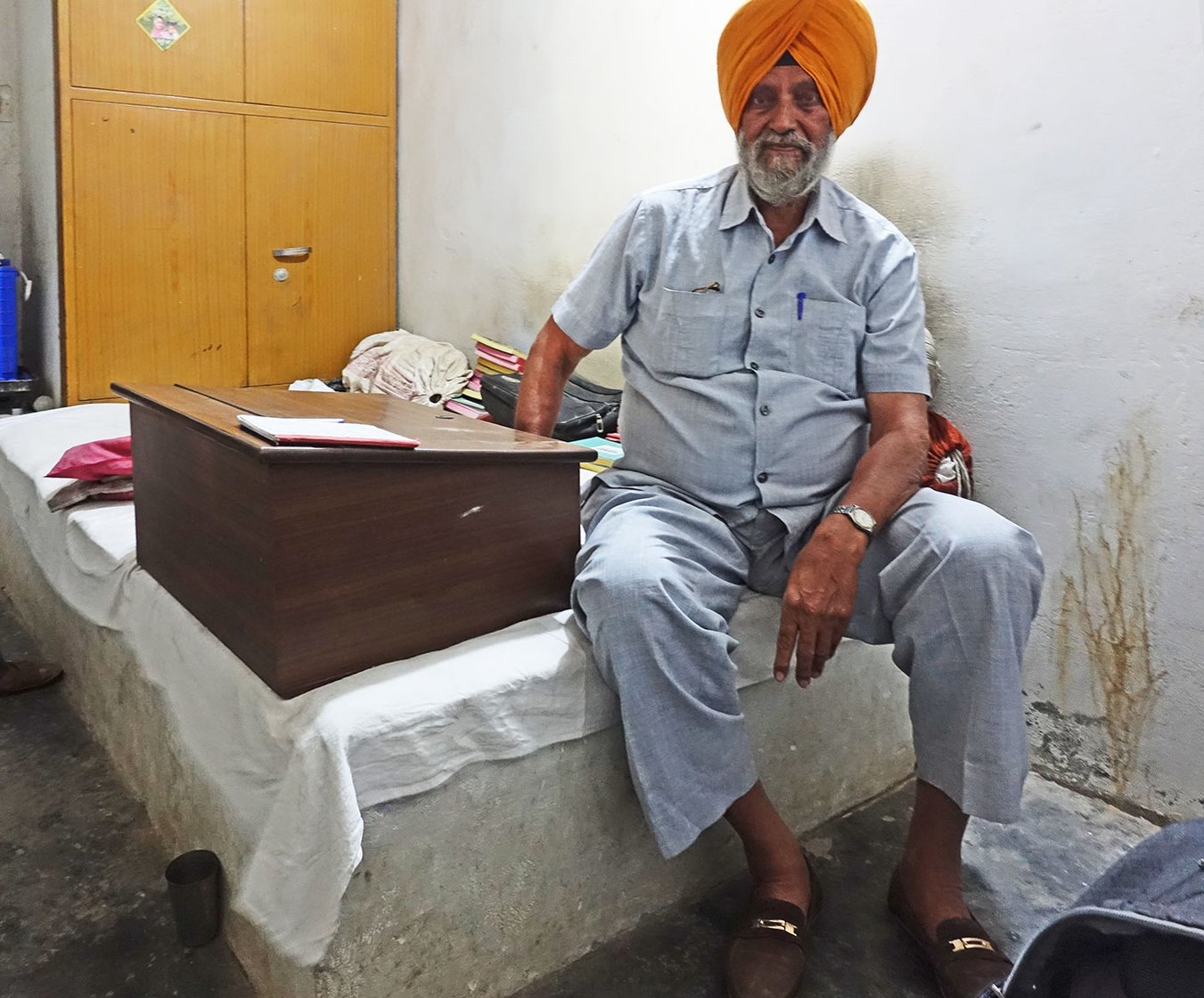A man sitting on a bed in an orange turban