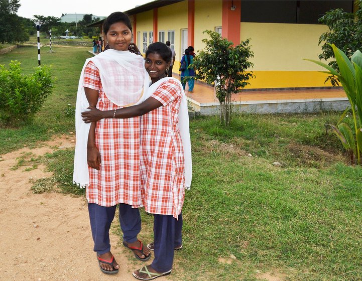 Two girls hugging in front of a school