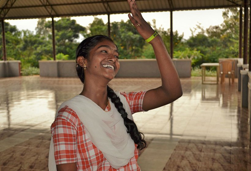 A girl laughing with one hand raised