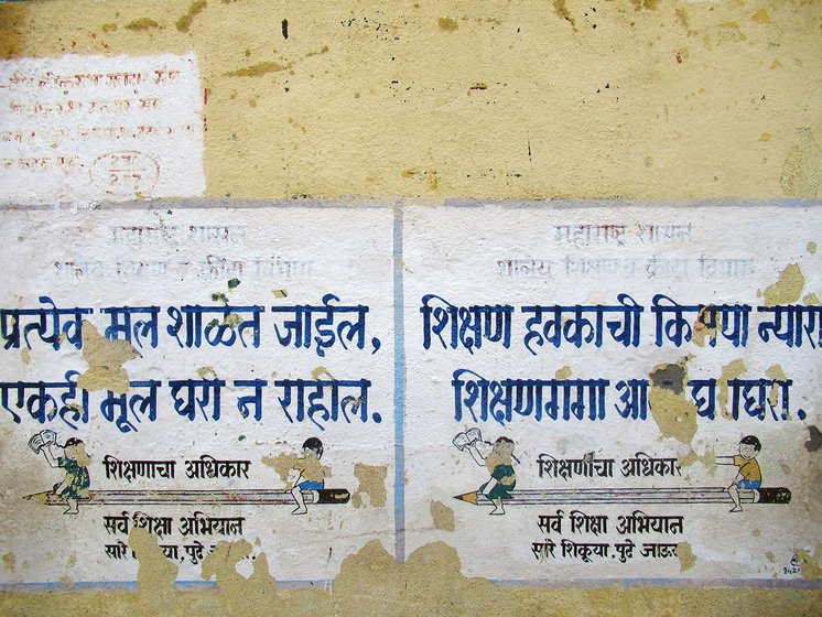 Torn posters on a yellow wall school wall in Marathi at Hatkarwadi village in Beed district of Maharashtra. It says, “Every kid will go to school, nobody will be at home”.