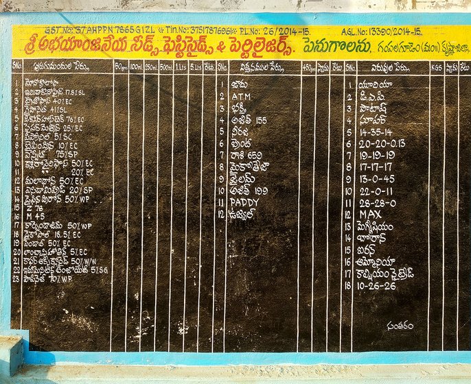 List of seeds, fertilizers and pesticides available in Abhayanjaneya Nursery, written on a wall. 