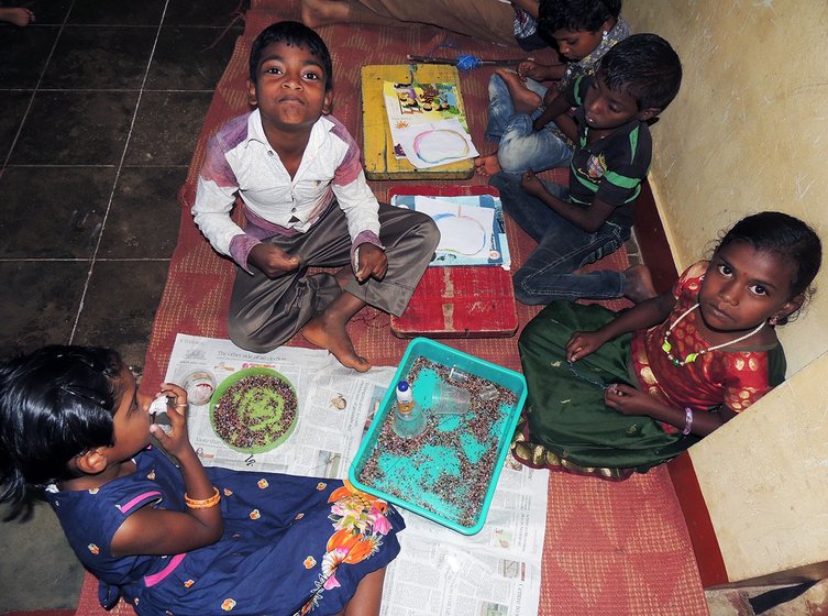 Adivasi children making bead chains in craft class