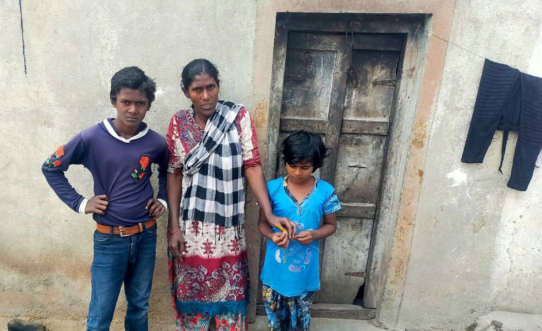 Azubi Ladaph with two of her four children, in front of their rented room in Umarga