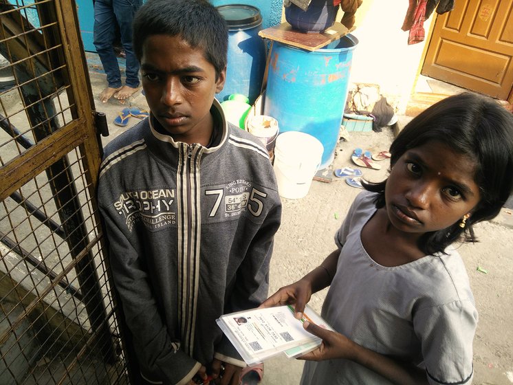 A young boy and girl holding their Aadhaar cards