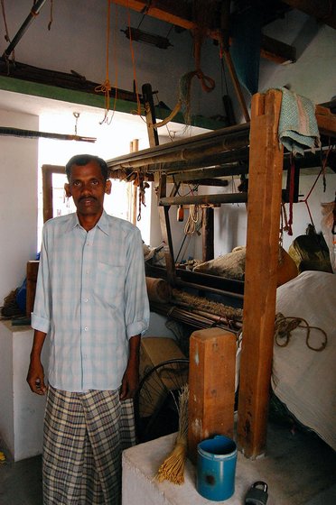 Vinayakam stands next to his disused loom.