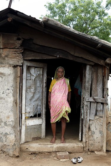 Left: A board announcing the resettlement of Sarubai's village Wadavali, which was submerged when the Warasgaon dam was built in`1994. Right: A few weeks ago, Sarubai's son asked her to leave his house; she now lives in this dilapidated hut at the entrance to the village