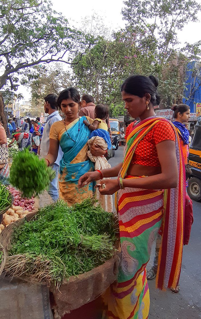 Pooja and Maya buying vegetables at the market.