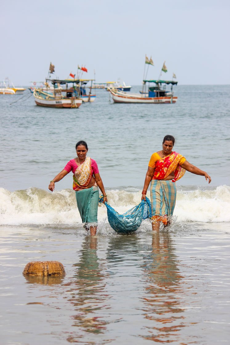 Left: 'We need to do something to fill our stomachs', says an elderly fisherwoman, as she walks a kilometre across Dandi beach in Malwan to the auction site to sell her family’s catch of tarli (sardine). Right: Women wash the fish to be to be salted and sun-dried 

