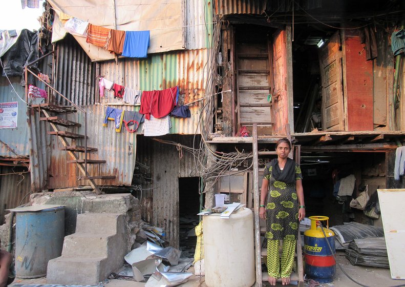 A woman standing on a ladder amidst hutments in Dharavi, a slum in Mumbai