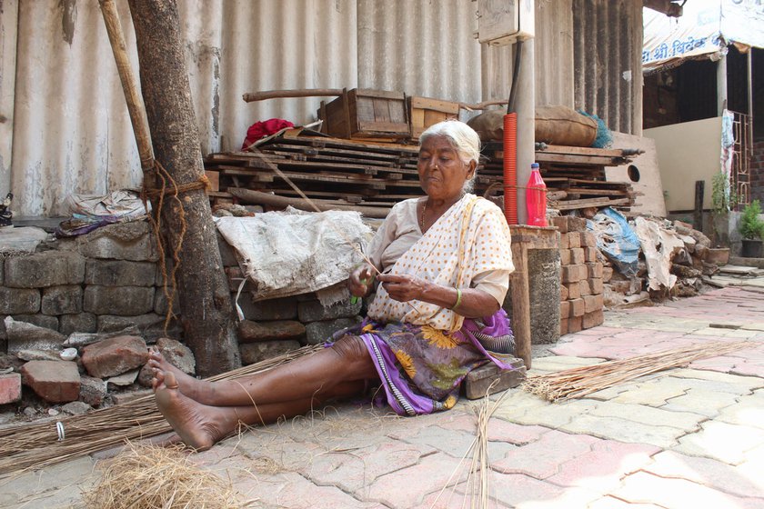Outside their home in Umela village. Suman’s mother, Nanda (right) making a broom from dried coconut palm leaves.