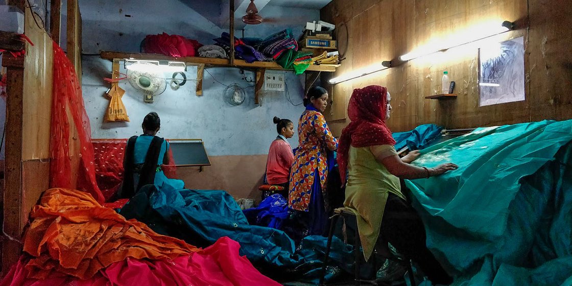 Women at work in a textile factory in Mina Nagar as they cut extra threads off the saris. They clock in 8 hours of work every day between 9am to 5pm, and earn an average of Rs. 5,000-7,000 per month