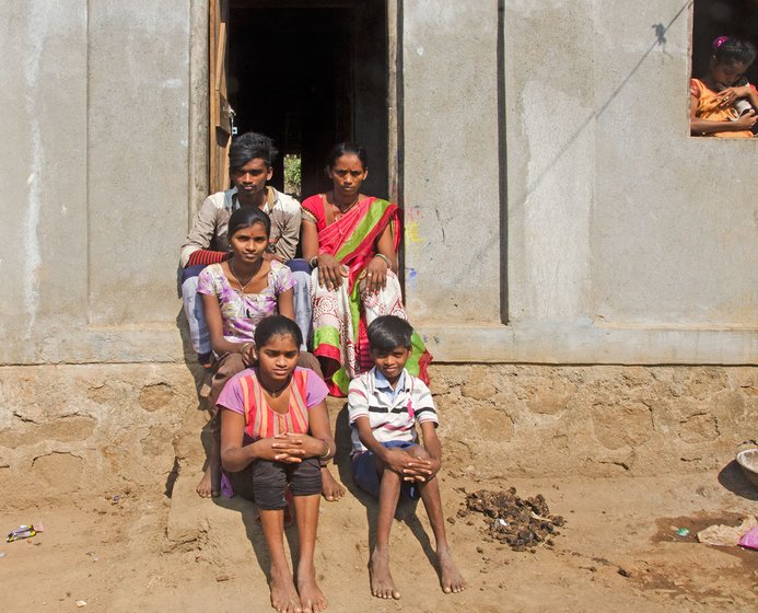 Tulshi with her children Kashinath (top row left), Munni (2nd row), Geeta (3rd row left) and Kashinath (3rd row right), sitting in the doorway of their house