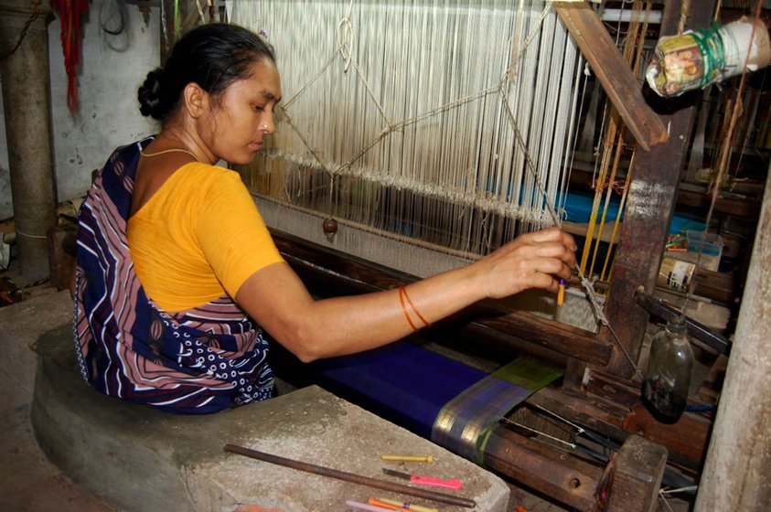 Lakshmi weaves a silk-cotton saree. She herself wears a synthetic one