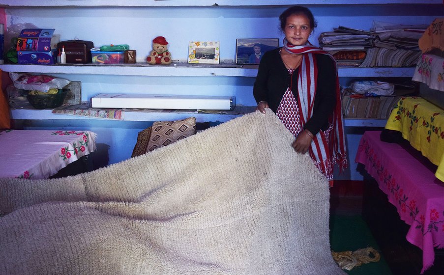Woman showing a thick banket (chutka) inside her home.