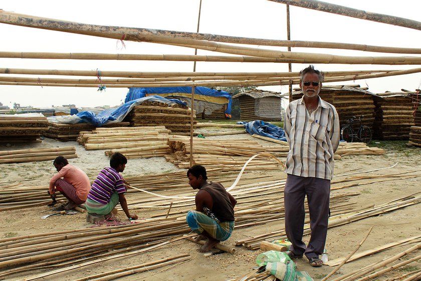 Radhakrishna Mandal (extreme right), is a contractor. Workers working on bamboo in the background.