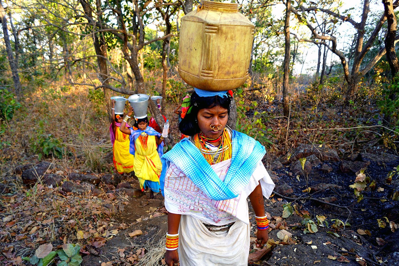 Tribal women walking uphill carrying water on their heads 