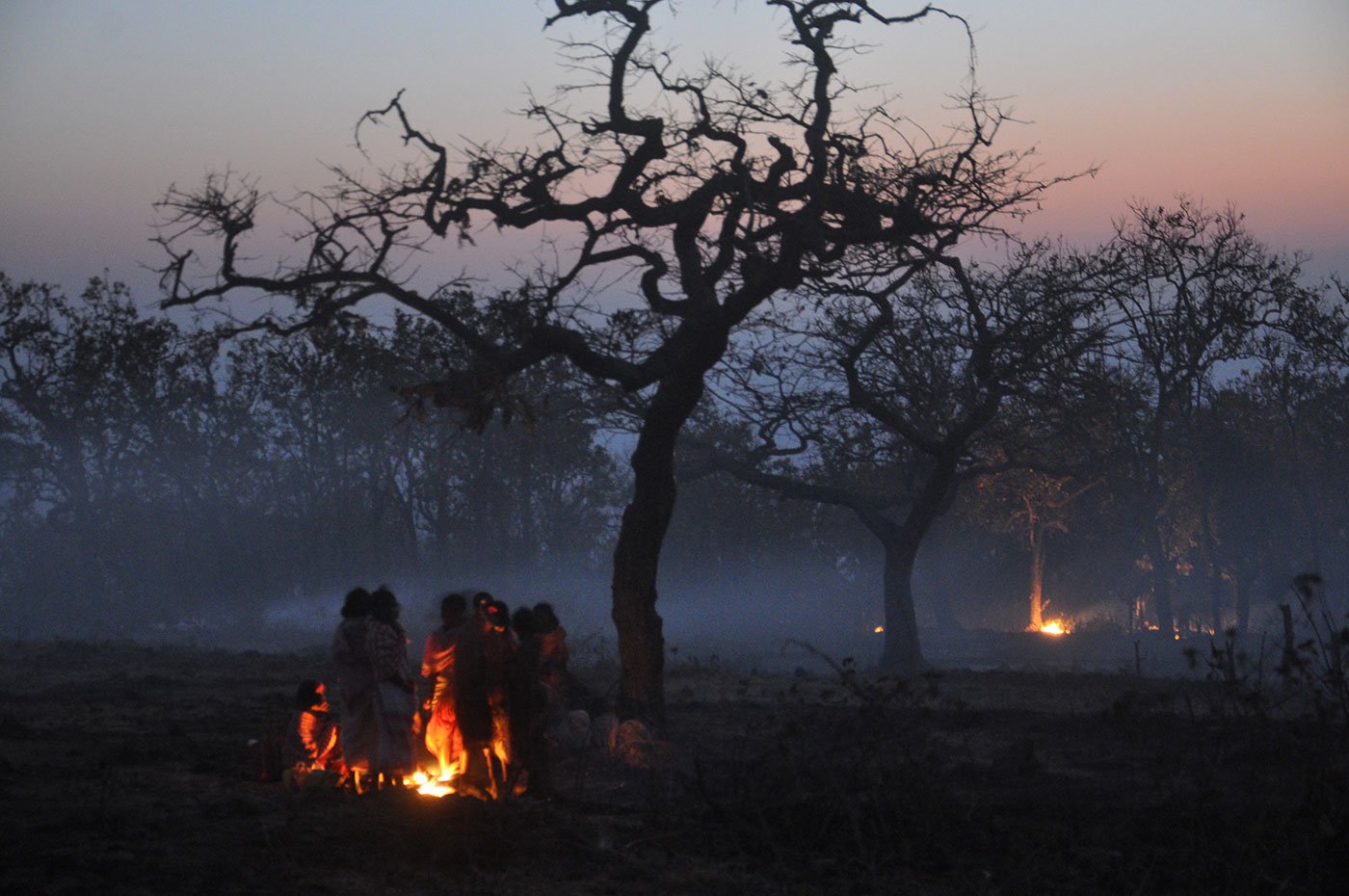 Tribals huddled next to a campfire in the evening