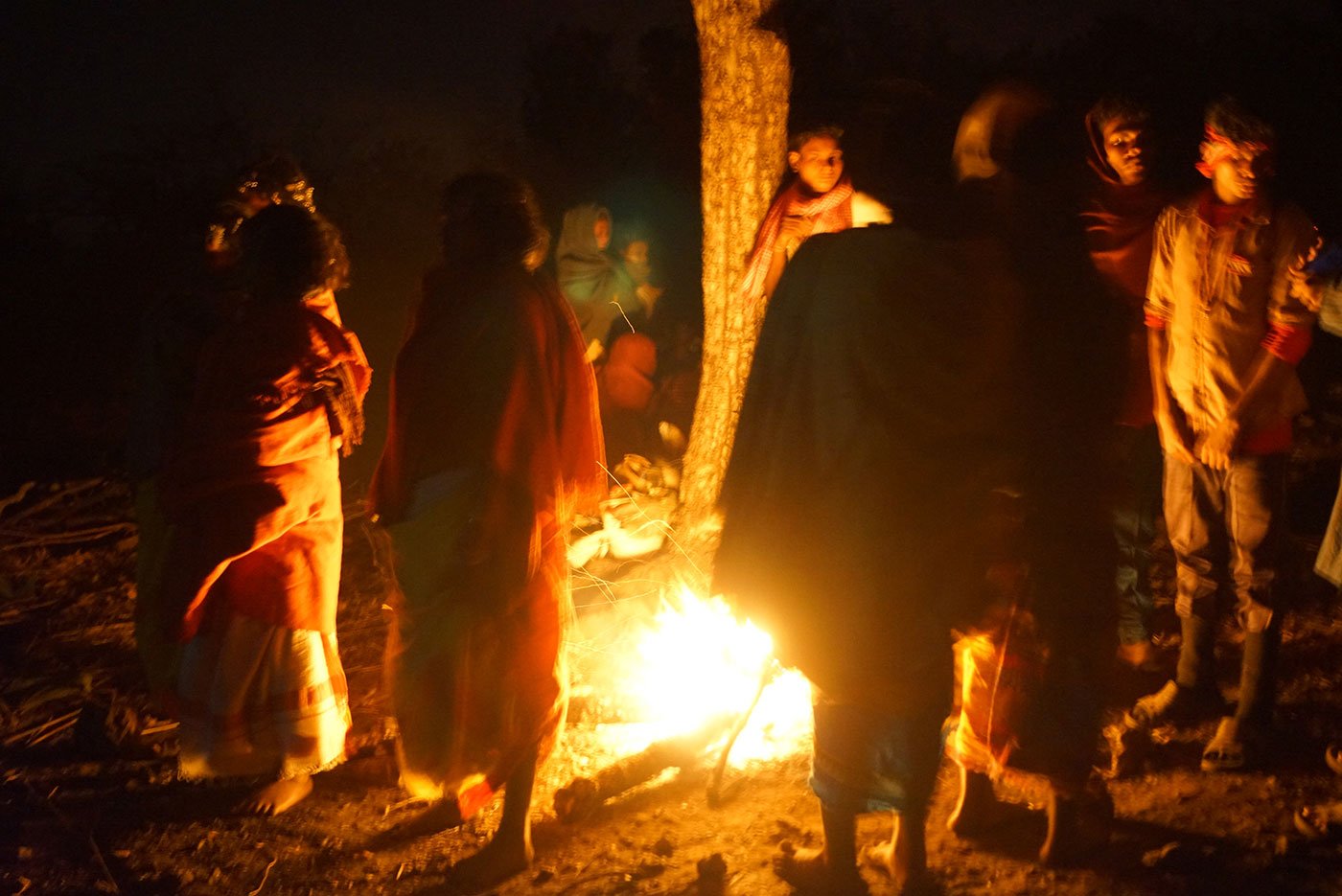 Tribals standing around a campfire at night