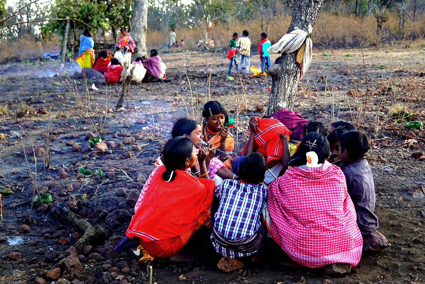 Groups of tribals sitting on the ground after the festivities