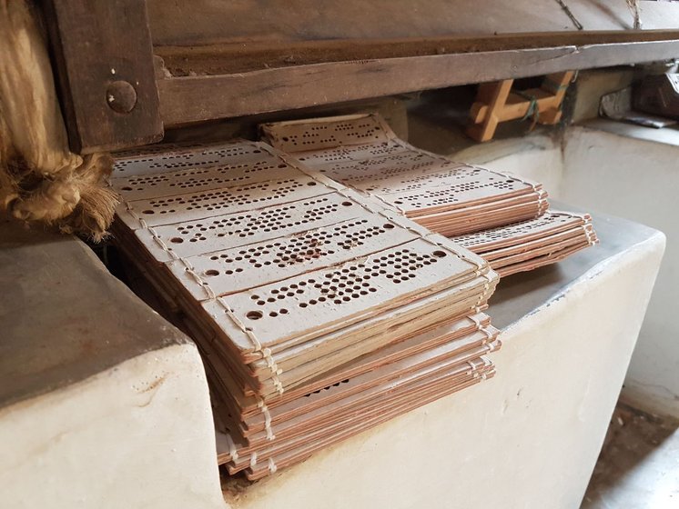 Stacks of punched cards to be used in the jacquard machine, kept in a corner. Shot inside Mani's house.