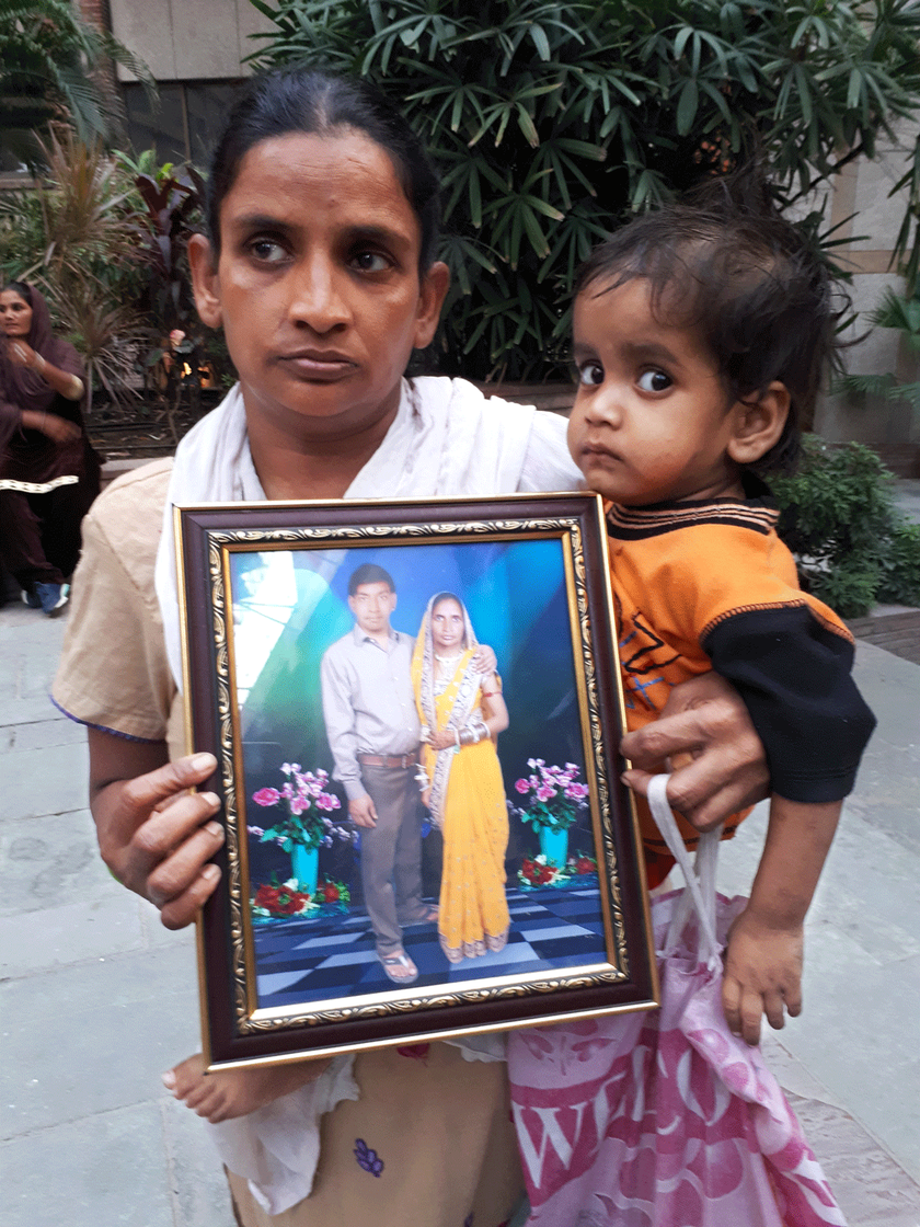 Rani holds her son in one hand and a frame of her and her husband on the other.
