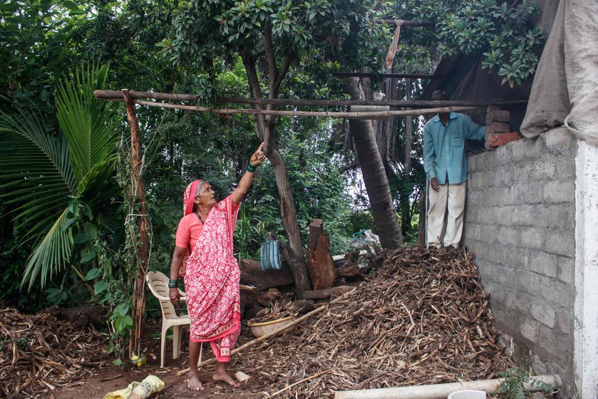 The women in the family also participated in the building of the jhopdi , between their work on the farm. Kusum Gaikwad (left) is winnowing the grains and talking to Vishnu (right) as he works