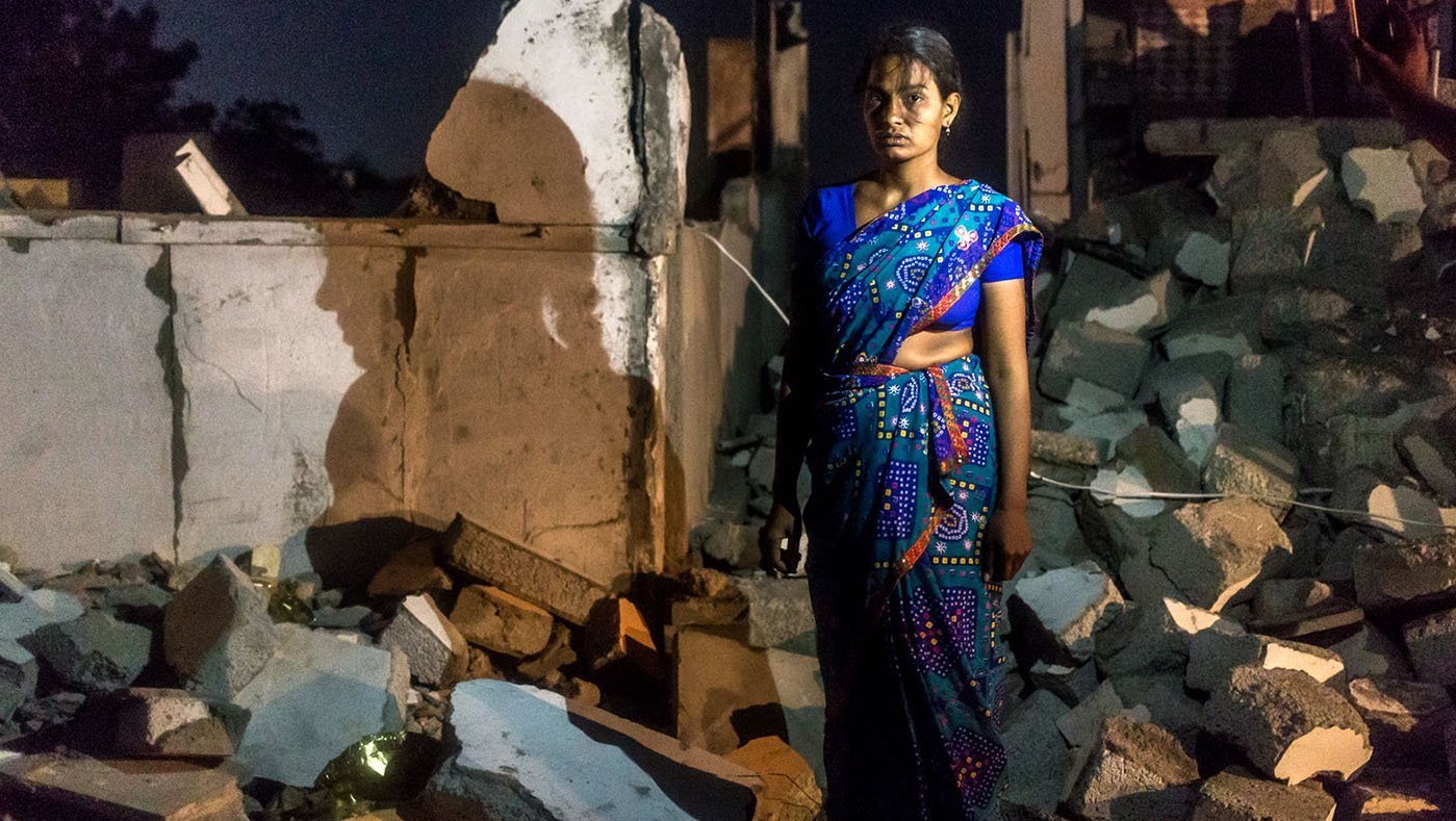 woman standing near ruins of home