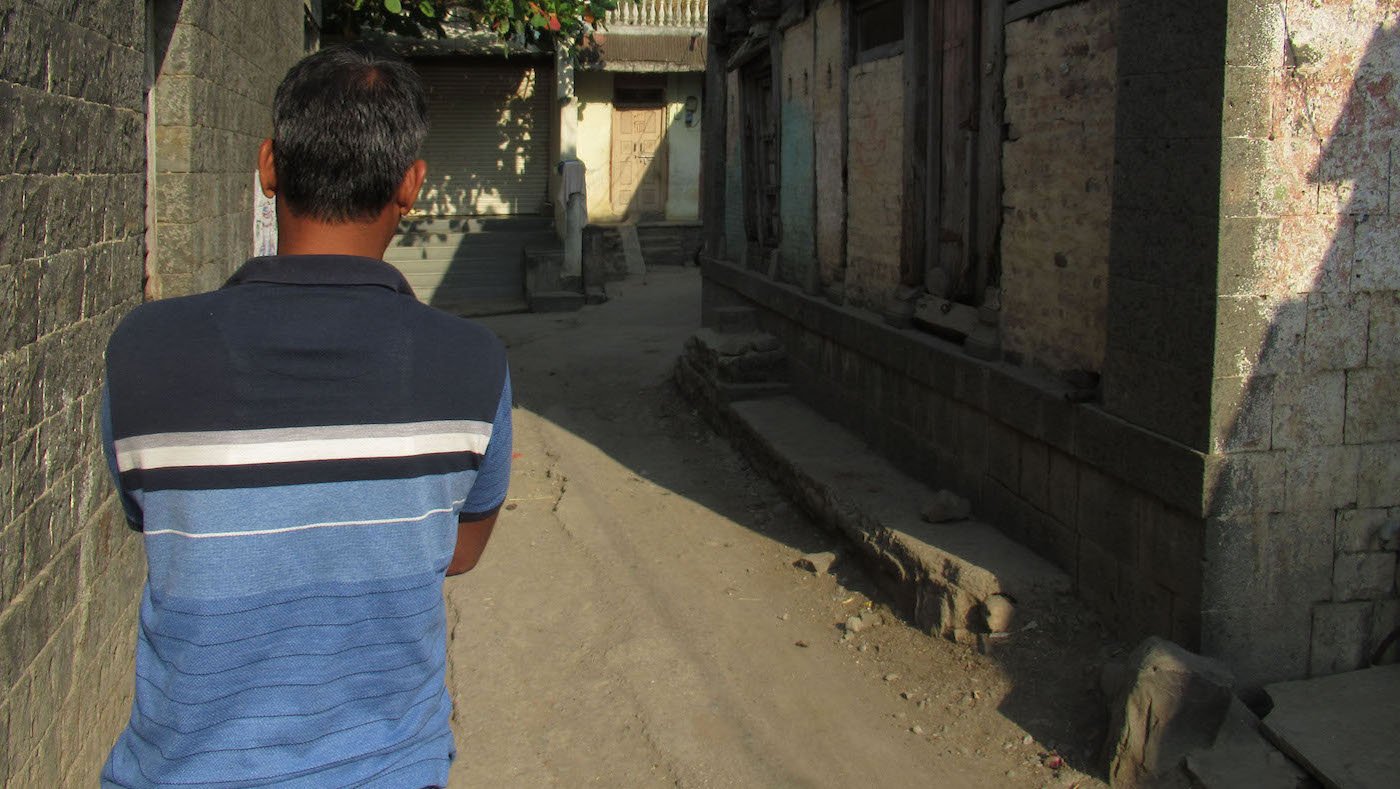 man with back towards camera walking on empty village street