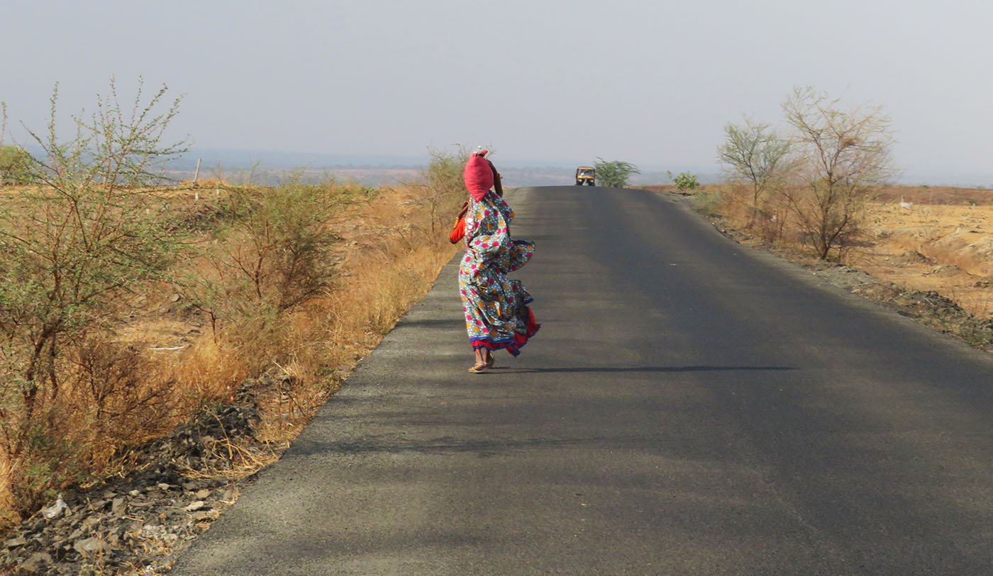 woman walking on road carrying water