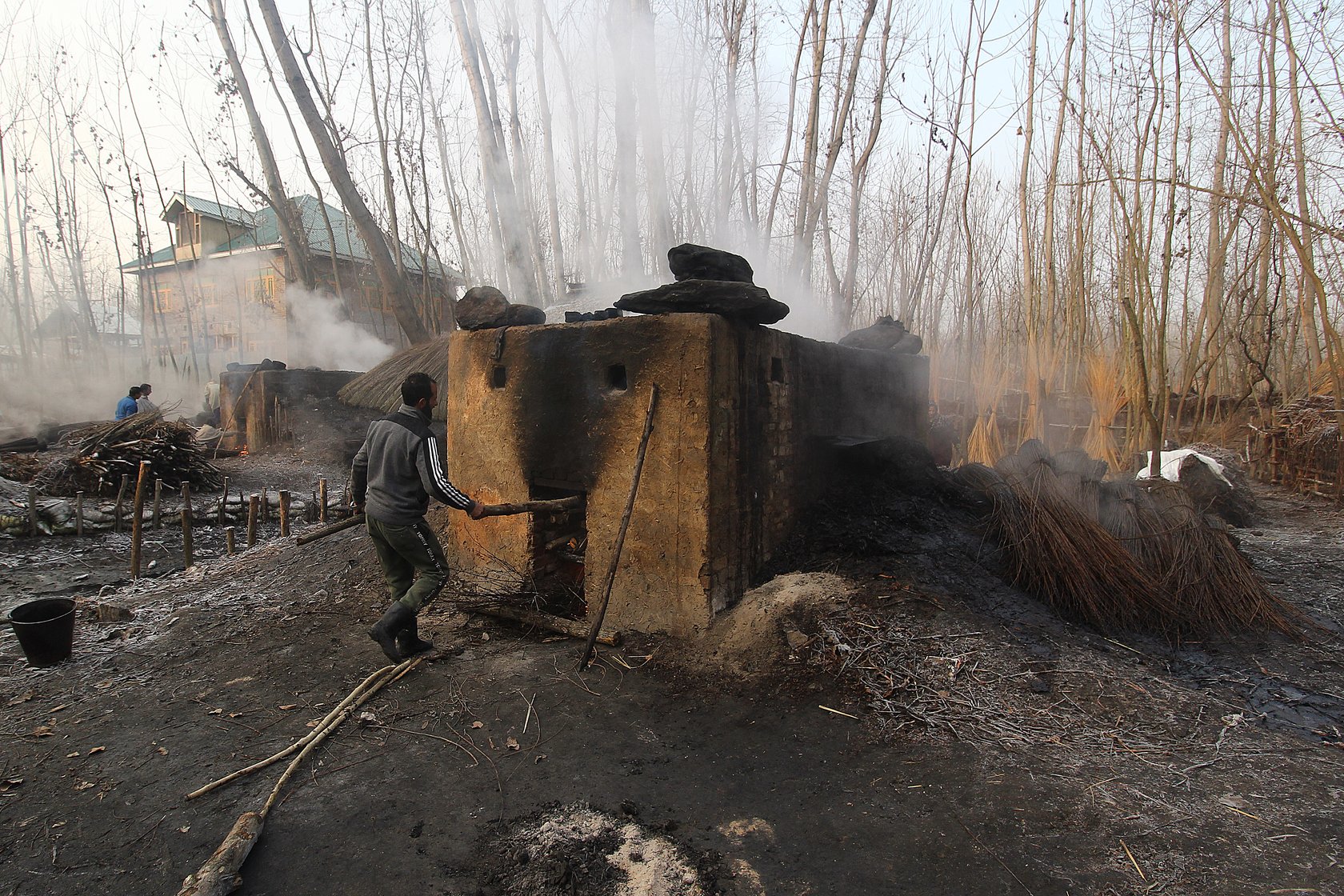 Waseem Ahmad, 32, a resident of Umerhere, fills firewood in the oven in which the wicker is to be boiled overnight