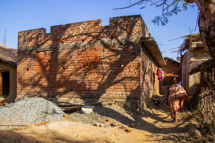 Supari Putel in front of her mud house and the family's incomplete house (right) under the Pradhan Mantri Awaas Yojana: 'This house cost me my husband'