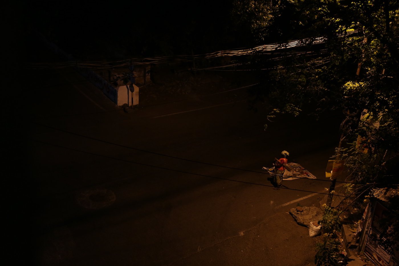 A woman stands alone in the dark after collecting garbage from the streets