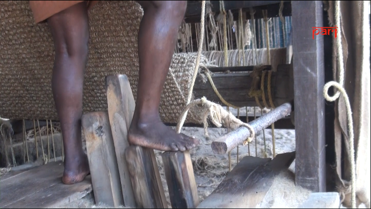 A coir weaver's feet in front of a coir loom