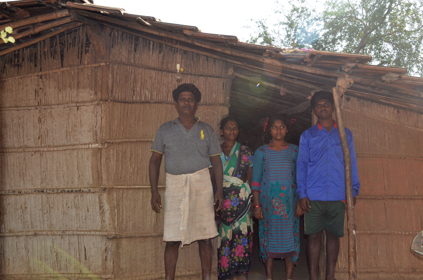 Family standing outside their hut