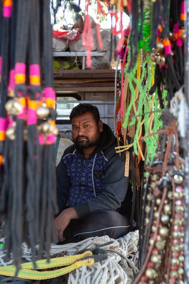 Shopkeeper sitting in his shop, selling accessorizes of livestock.